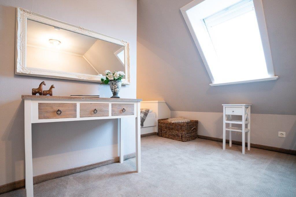Schlafzimmer mit Dachfenster, Schreibtisch und Spiegel an der Wand.