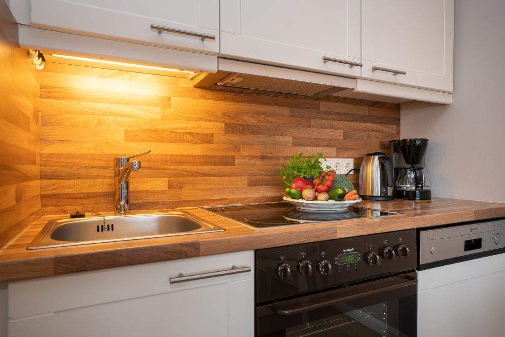 Küche mit Holzwand, Spüle, Herd und Obstschale
