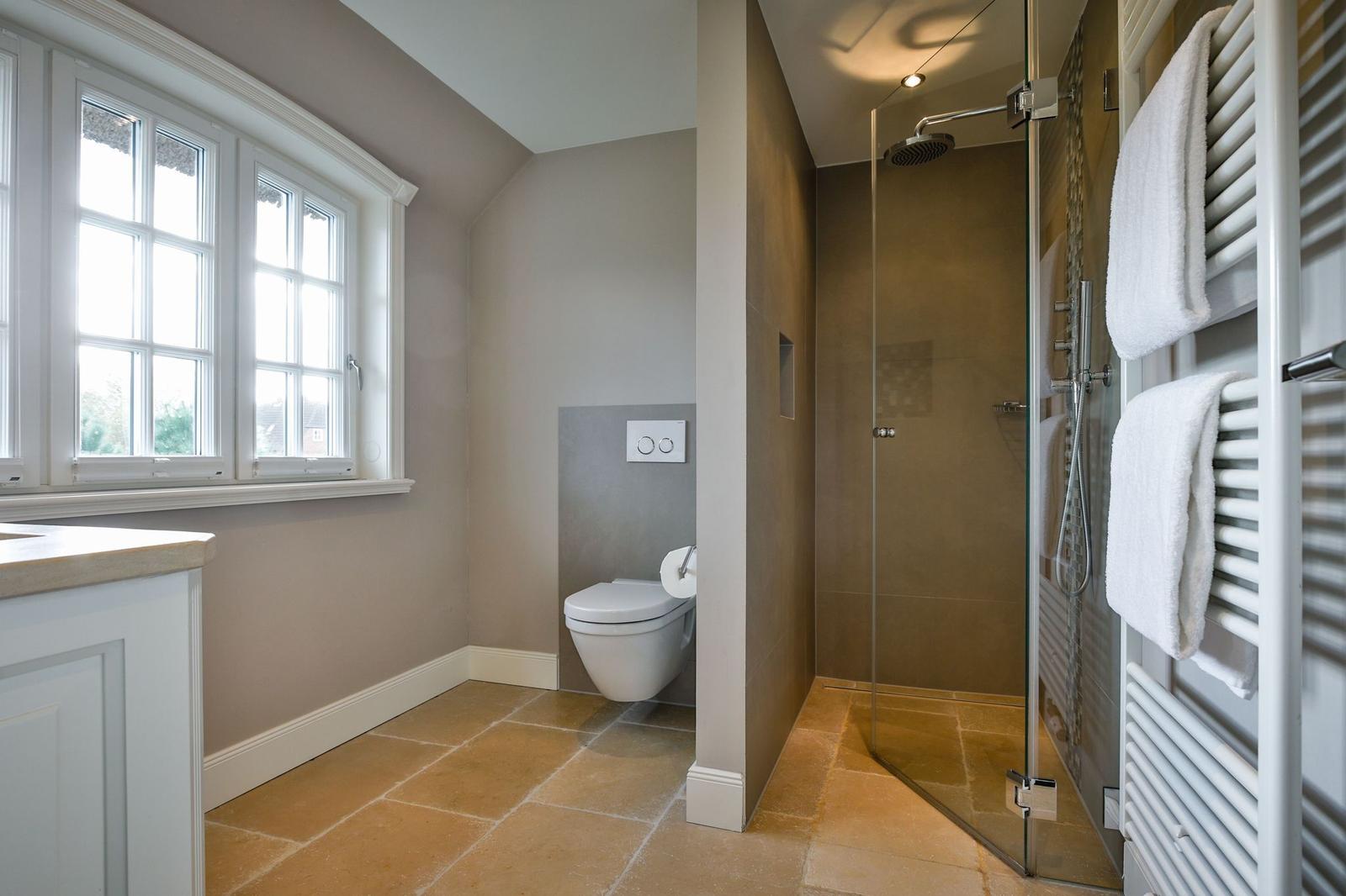 Badezimmer mit Dusche, Toilette und Fenster