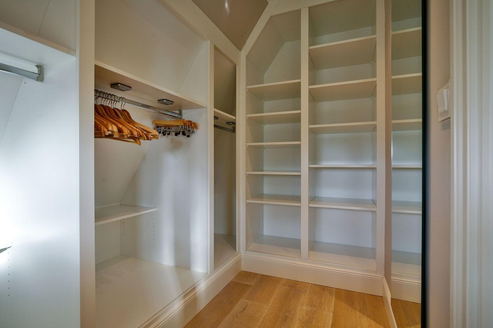 Großer Kleiderschrank mit Holzregalen und Hängern.