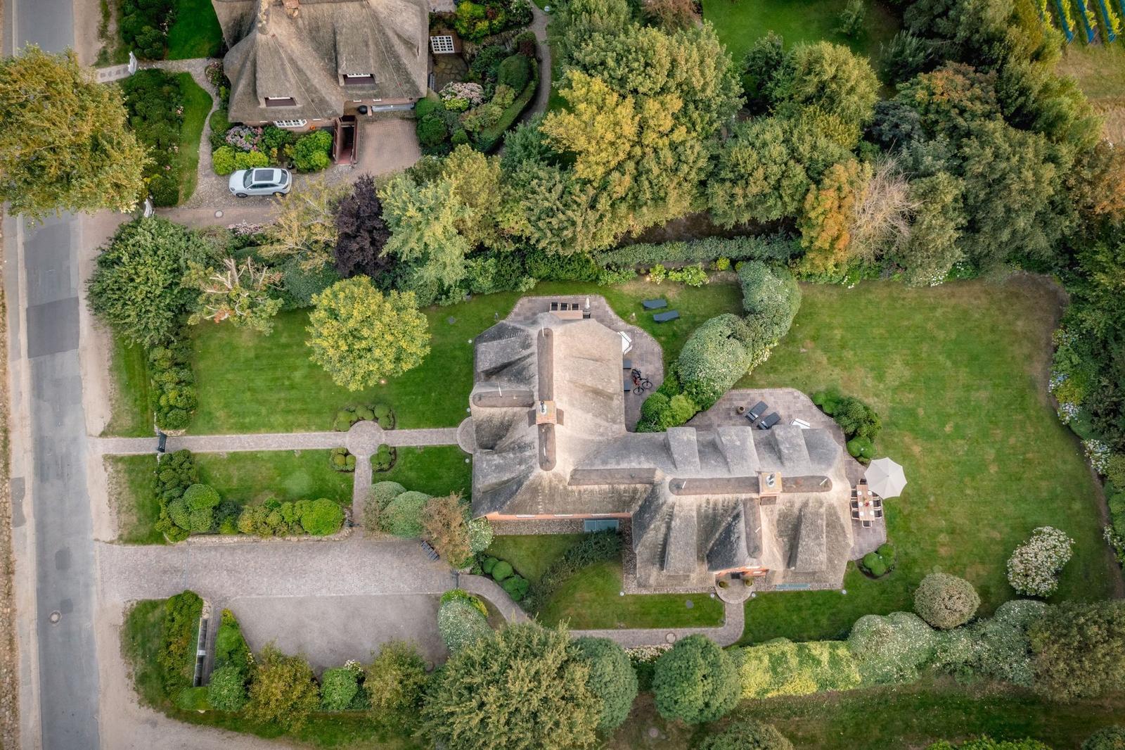 Luftbild einer Villa mit Dachstuhl, Garten und Parkplatz.