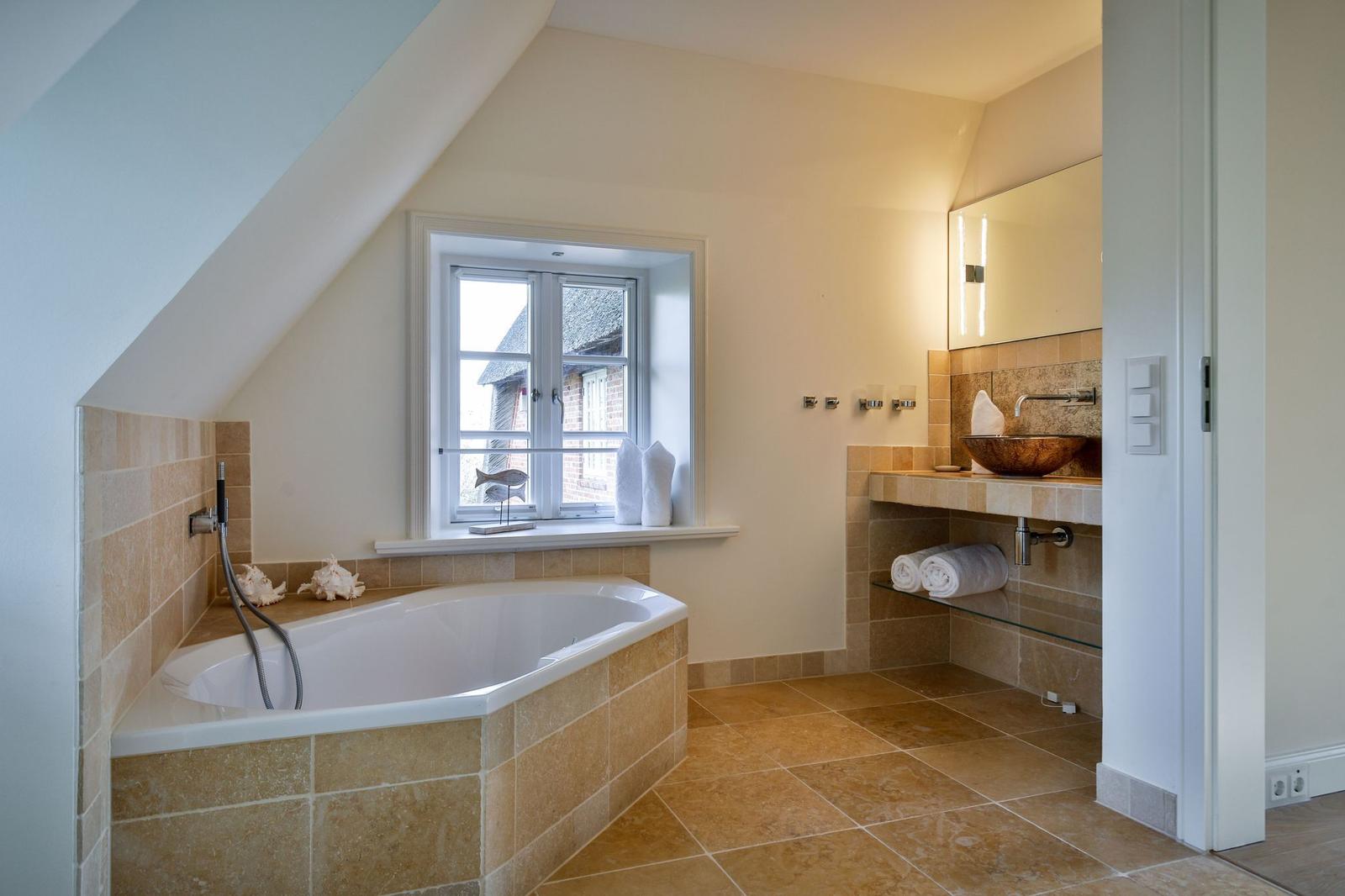 Badezimmer mit Badewanne, Waschbecken und Fenster
