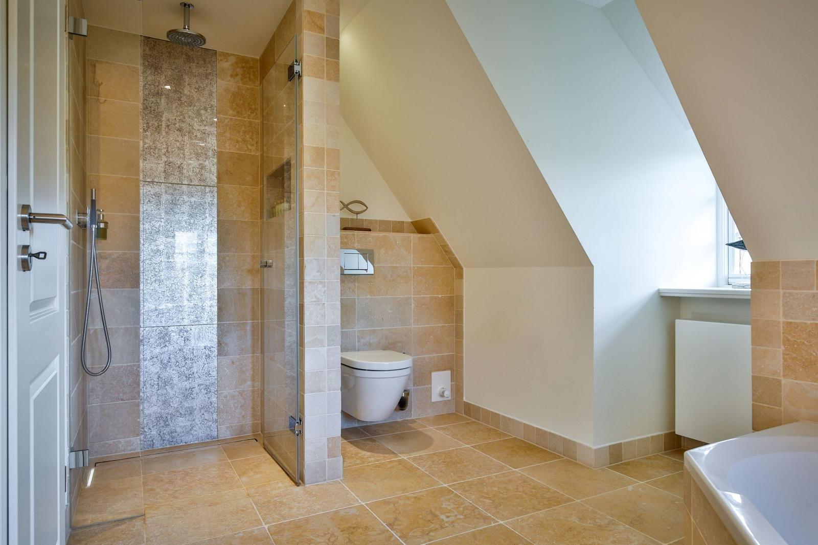 Dusche mit Glaswand, Toilette und Badewanne in Dachschrägen