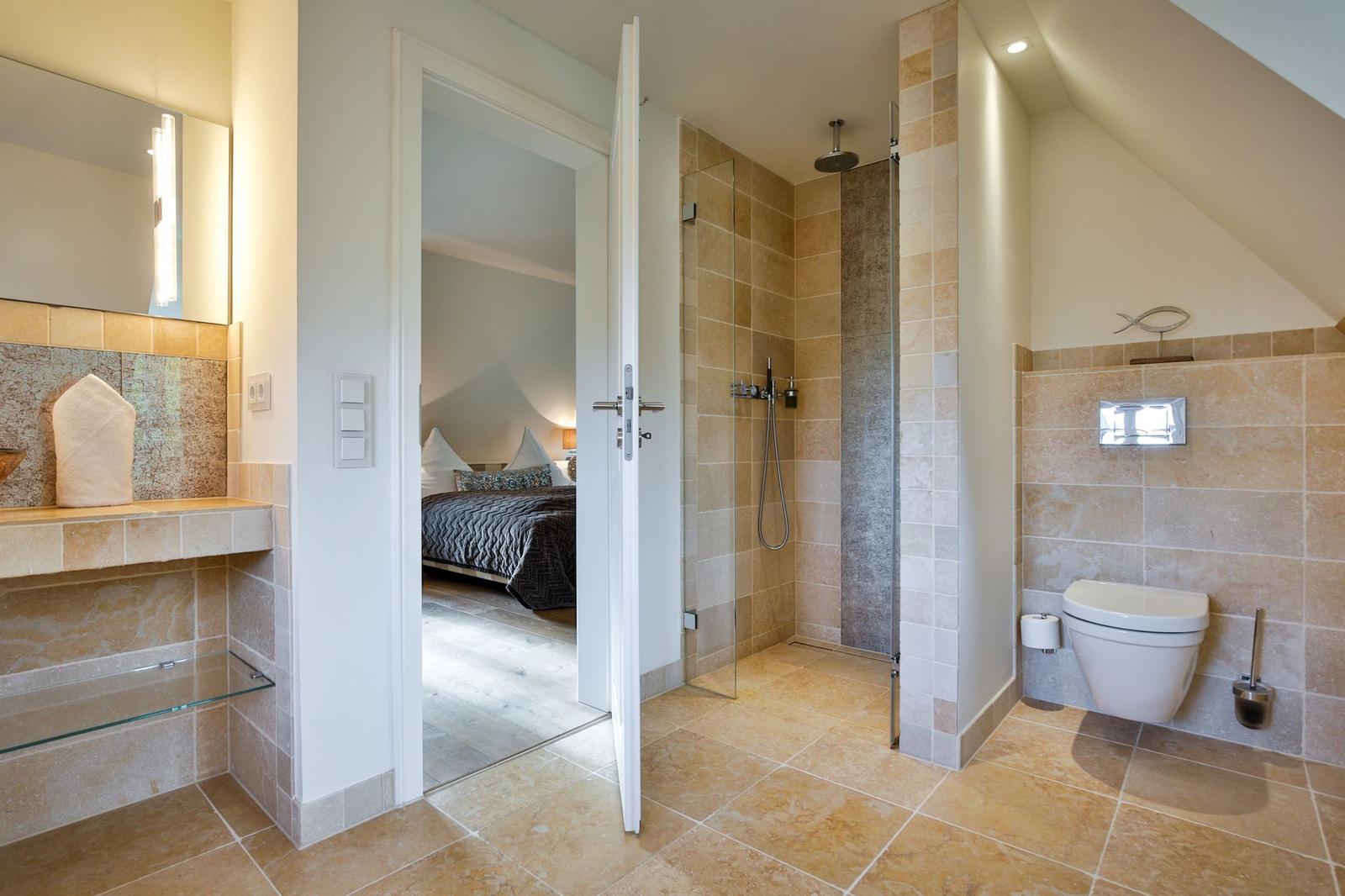Badezimmer mit Dusche, Toilette und Blick in Schlafzimmer