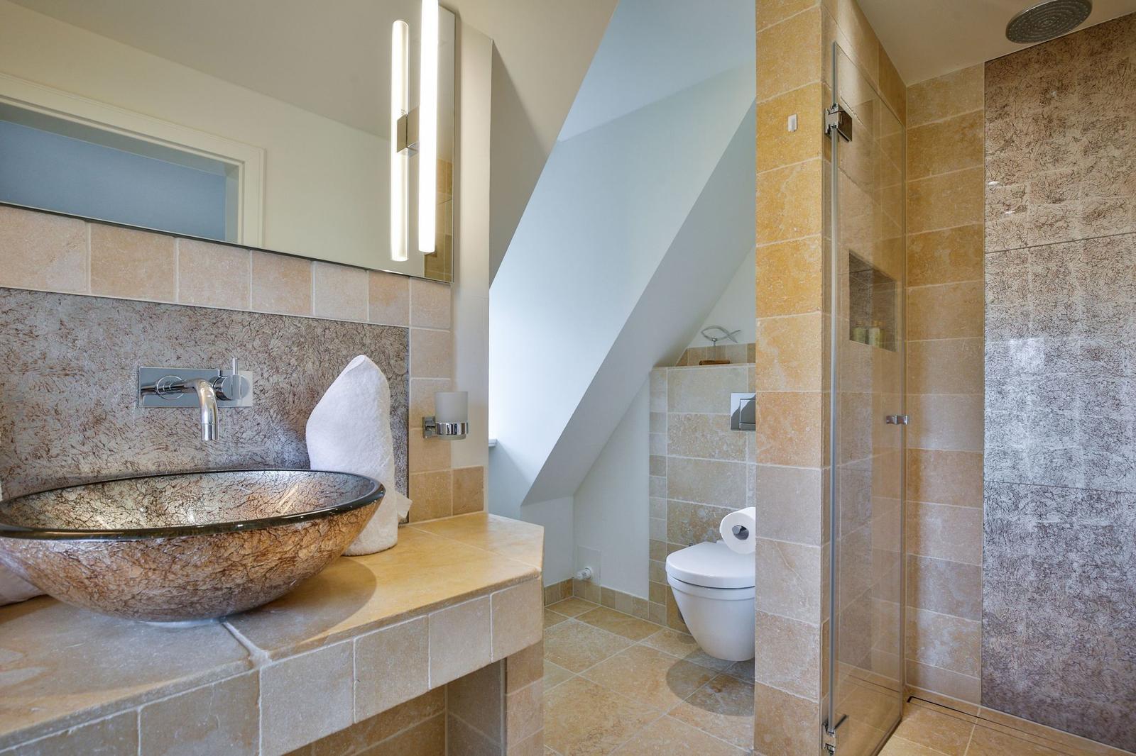 Badezimmer mit Dusche, Toilette und Waschtisch mit Keramikwaschschale.