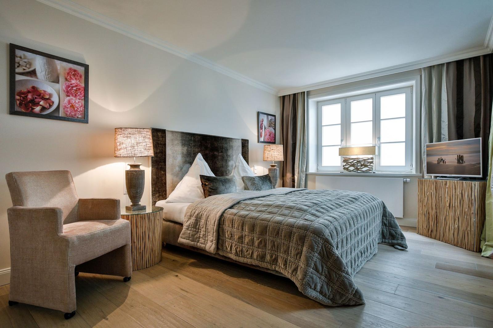 Schlafzimmer mit Bett, Sessel und Fenster