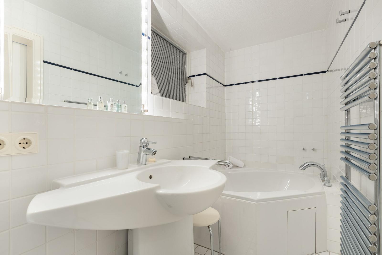 Badezimmer mit Waschbecken, Badewanne und Heizkörper