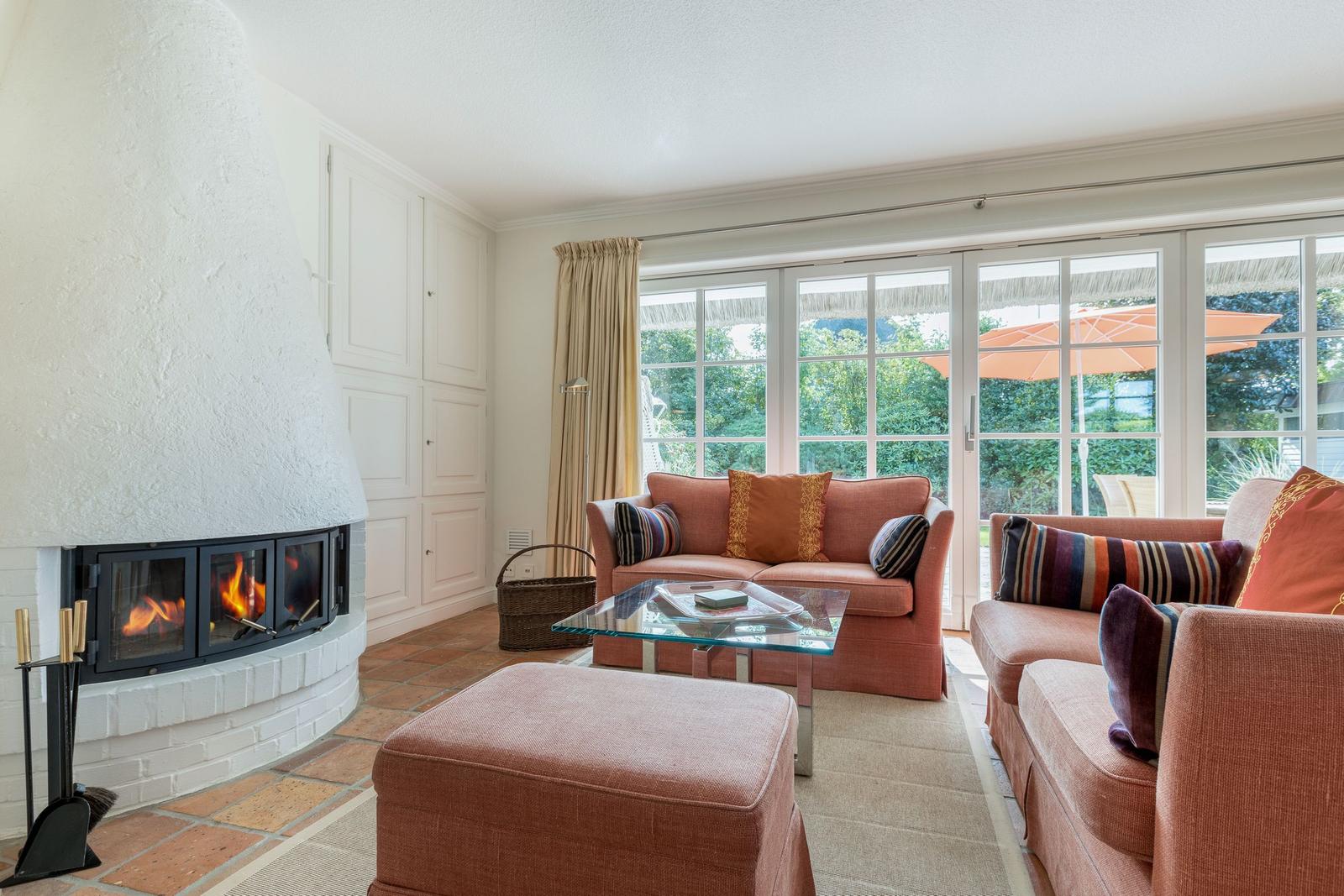 Wohnzimmer mit Kamin, Sofa und Blick auf Garten