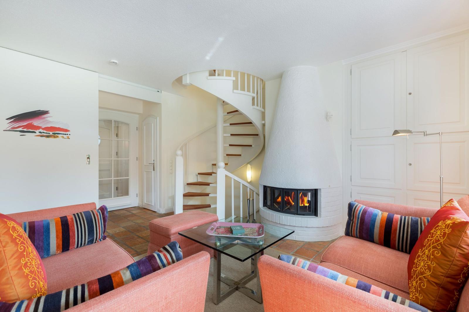 Wohnzimmer mit Kamin, Spiral-Treppe und orangefarbenen Sofas.