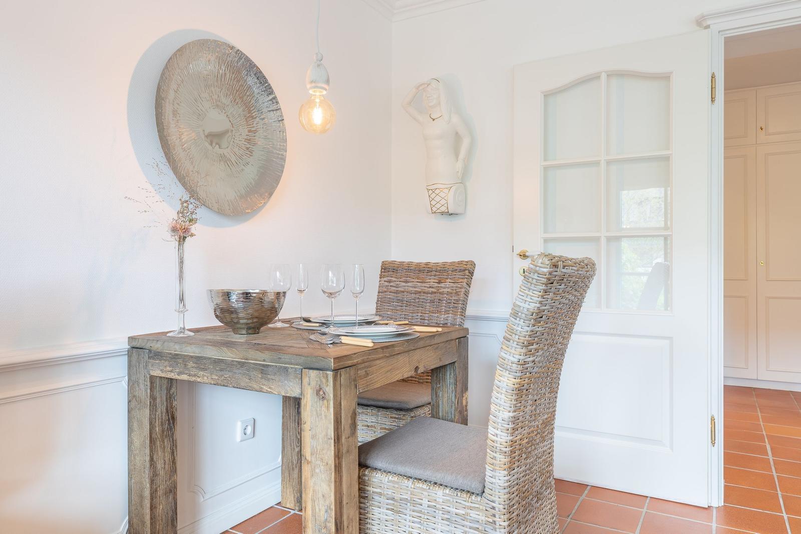 Dining room with rustic table, wicker chairs, and wall decor.
