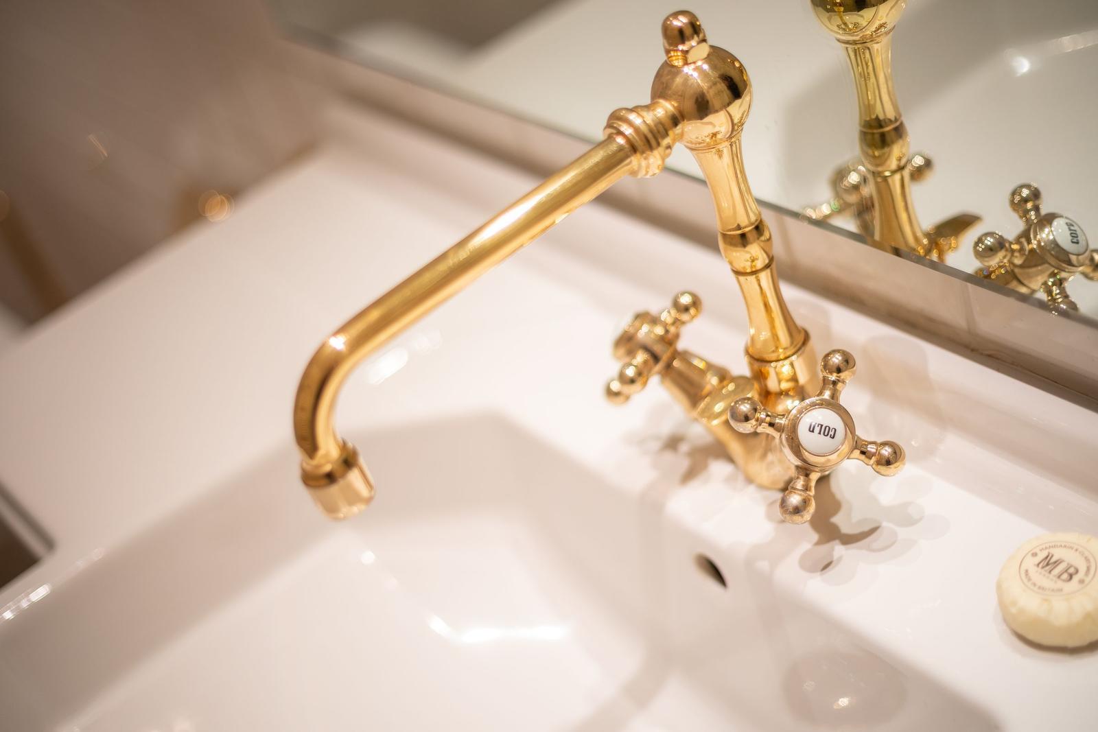 Gold faucet with knobs on white sink