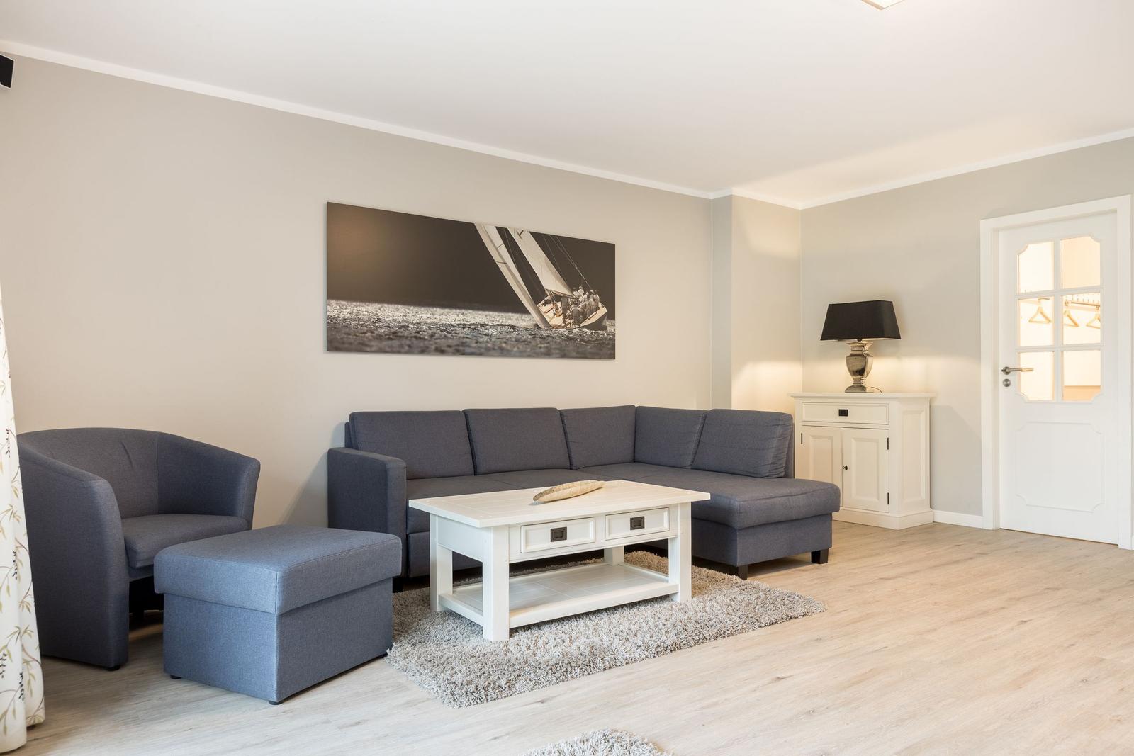 Wohnzimmer mit grauem Sofa, weißem Couchtisch und Wandbild
