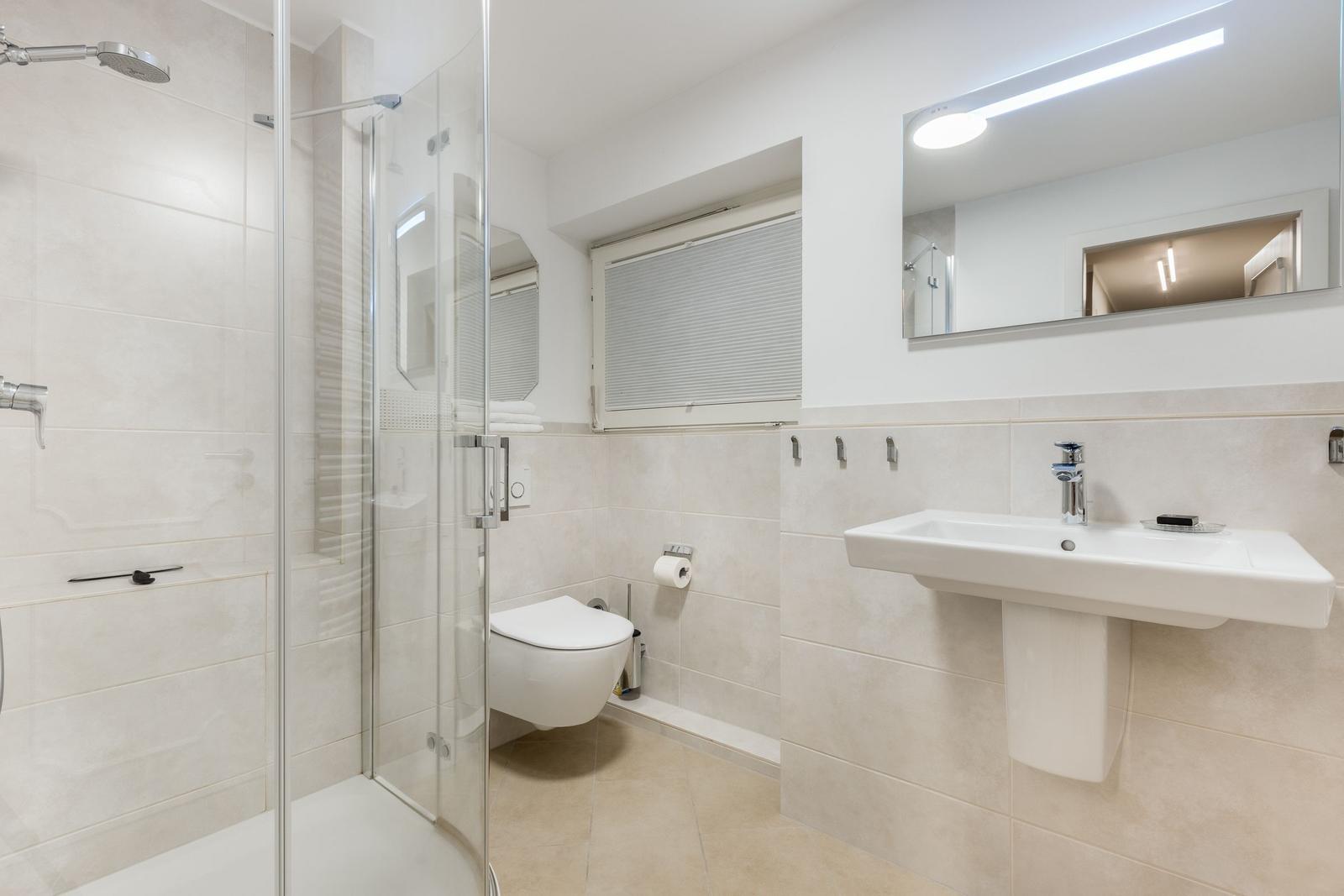 Badezimmer mit Dusche, Toilette und Waschbecken.