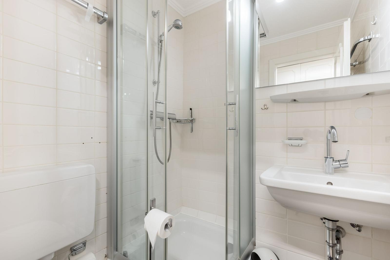 Badezimmer mit Dusche, Waschbecken und Toilette.