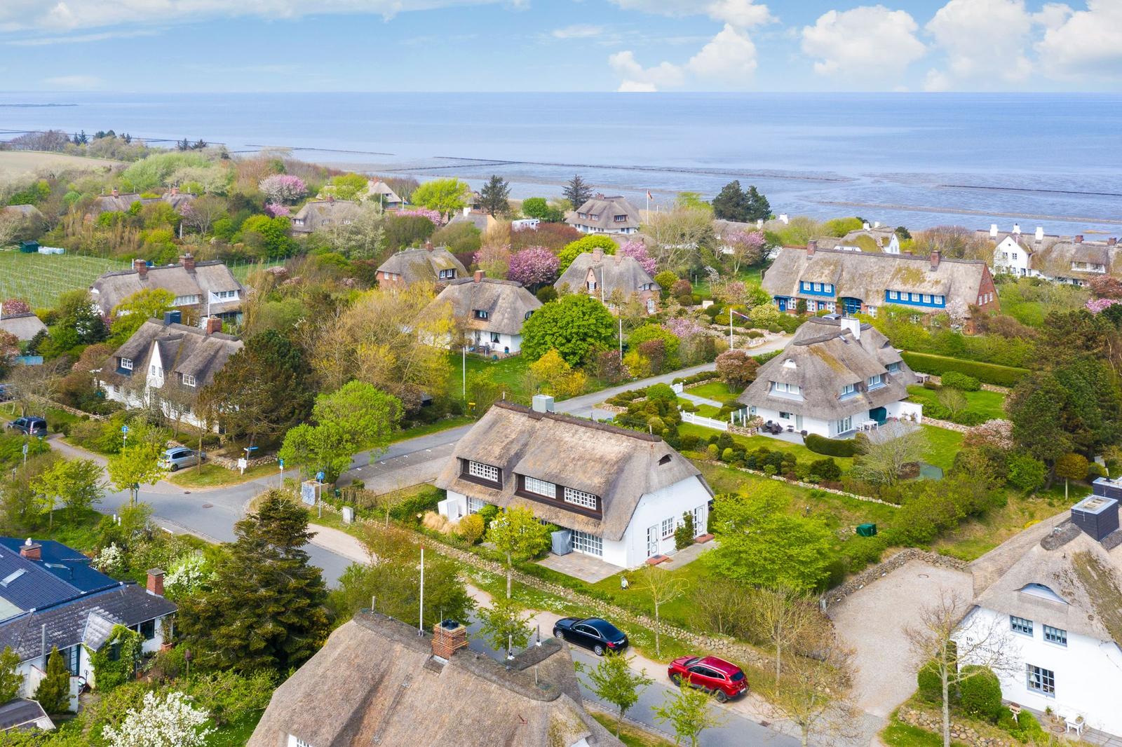 Dorf mit strohgedeckten Häusern und Blick aufs Meer
