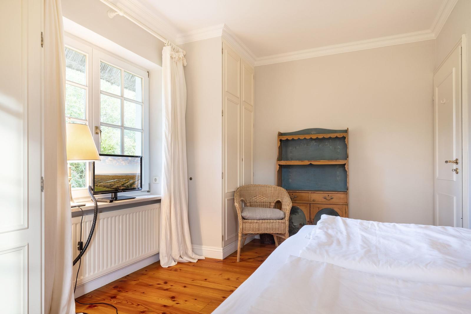 Schlafzimmer mit Bett, Stuhl und TV an Fenster