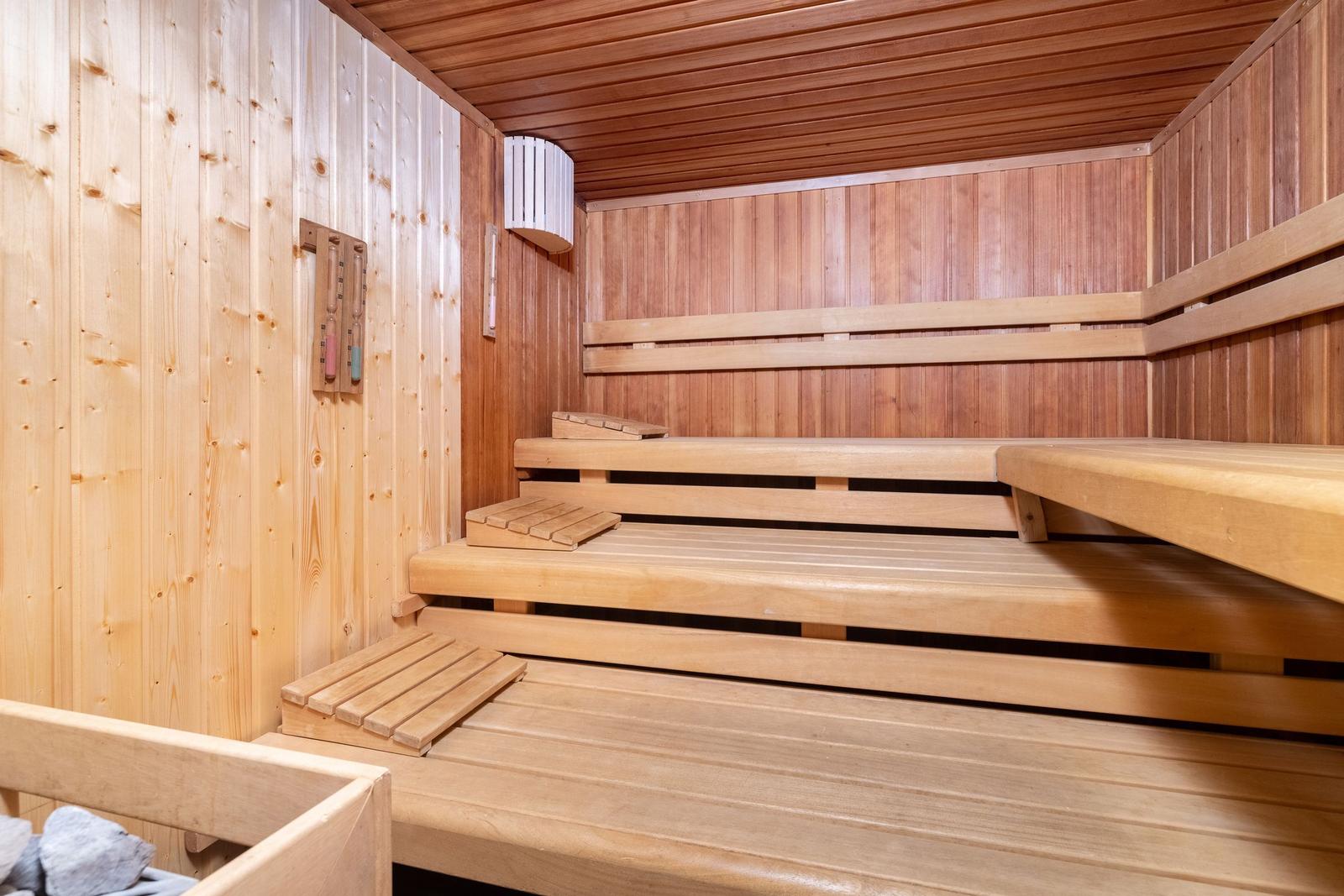 Sauna mit Holzbanken und Temperaturmessgerät an der Wand.