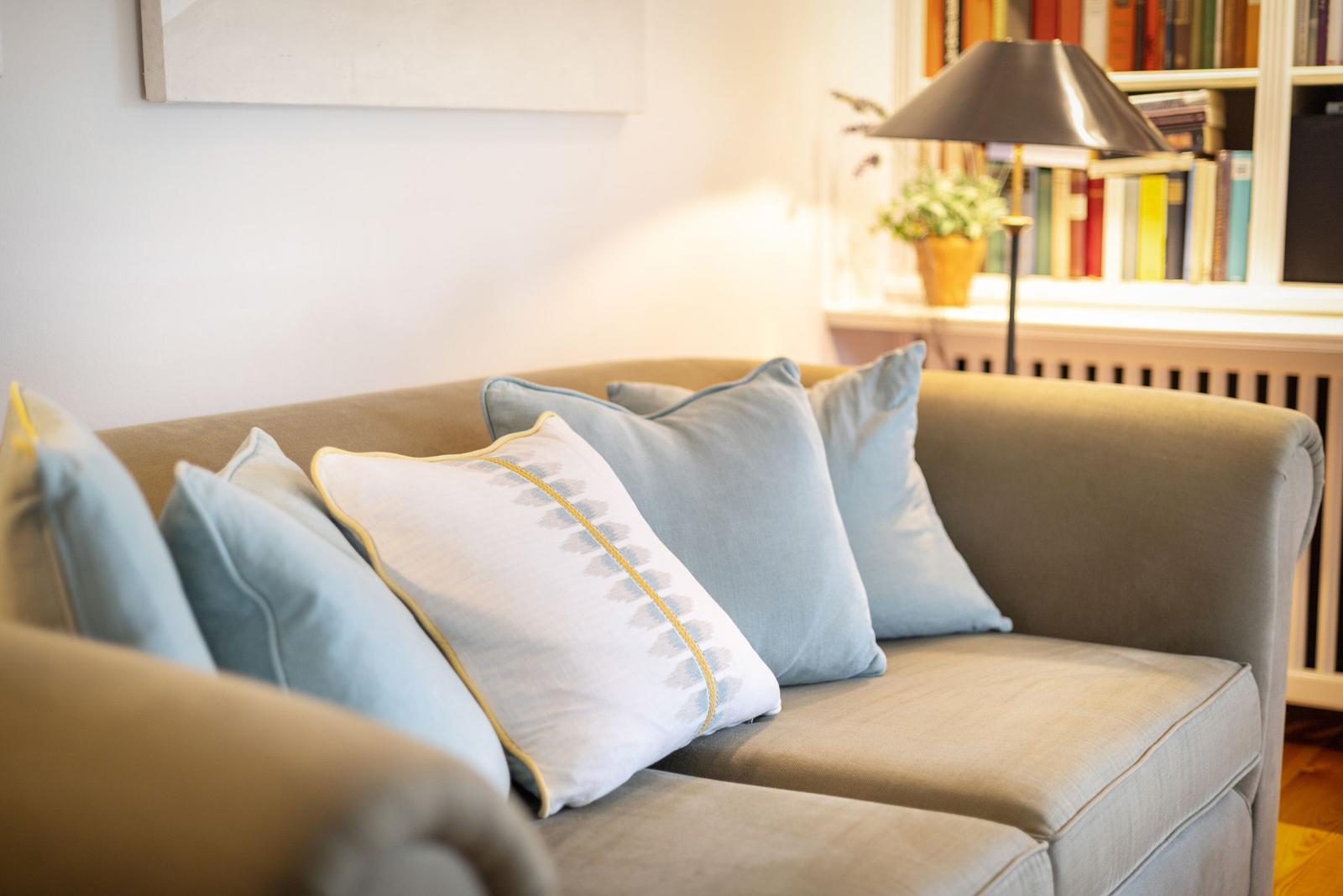 Ein Sofa mit Kissen und einer Lampe im Hintergrund.