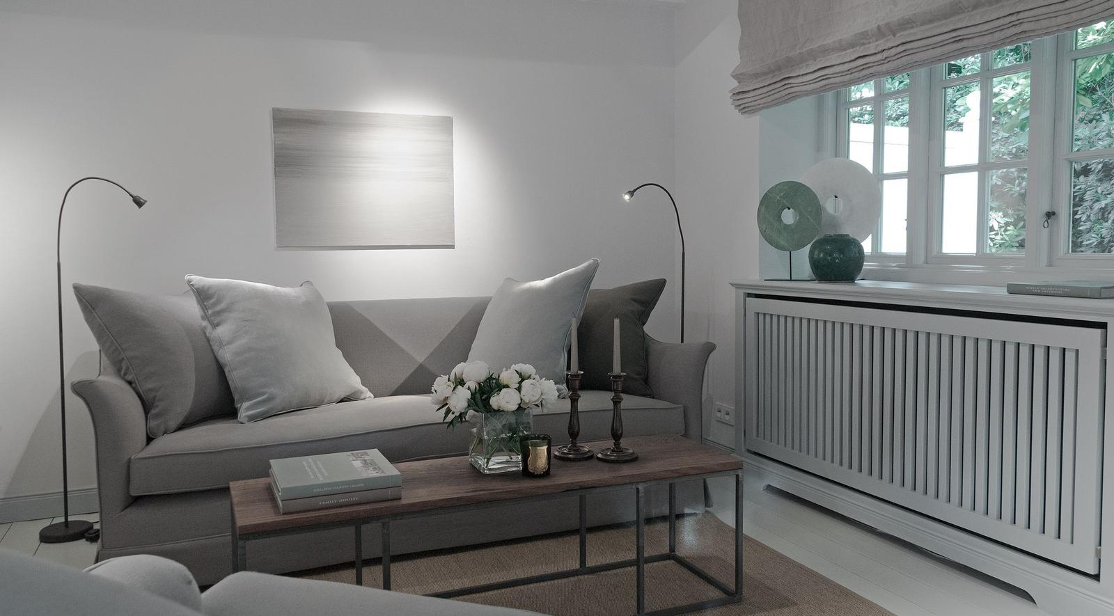 Living room with gray sofa, wooden table, and window with view of greenery.