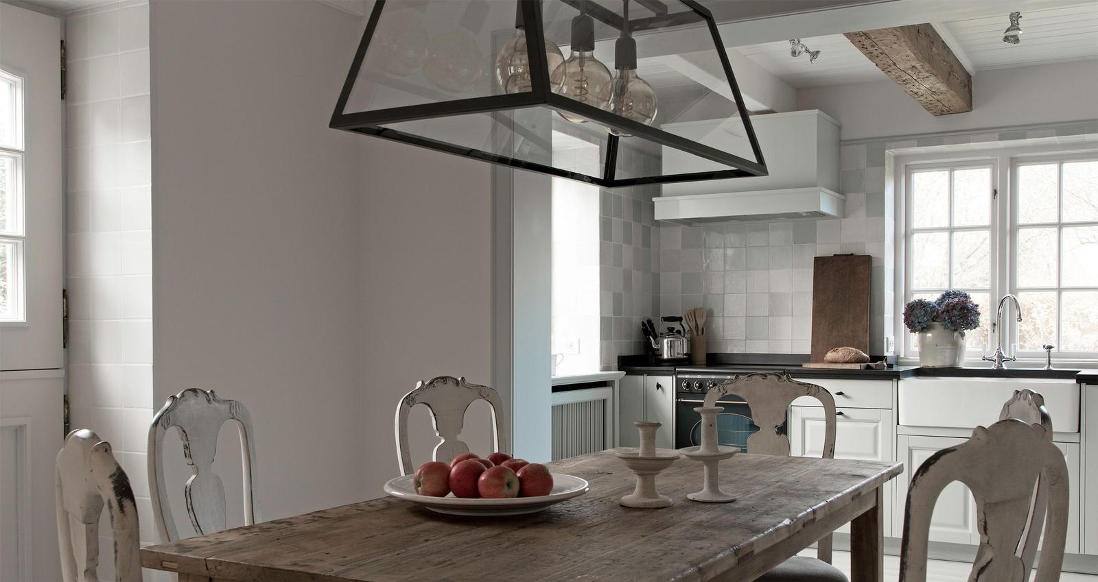 Dining room with wooden table, chairs, and kitchen area in the background.