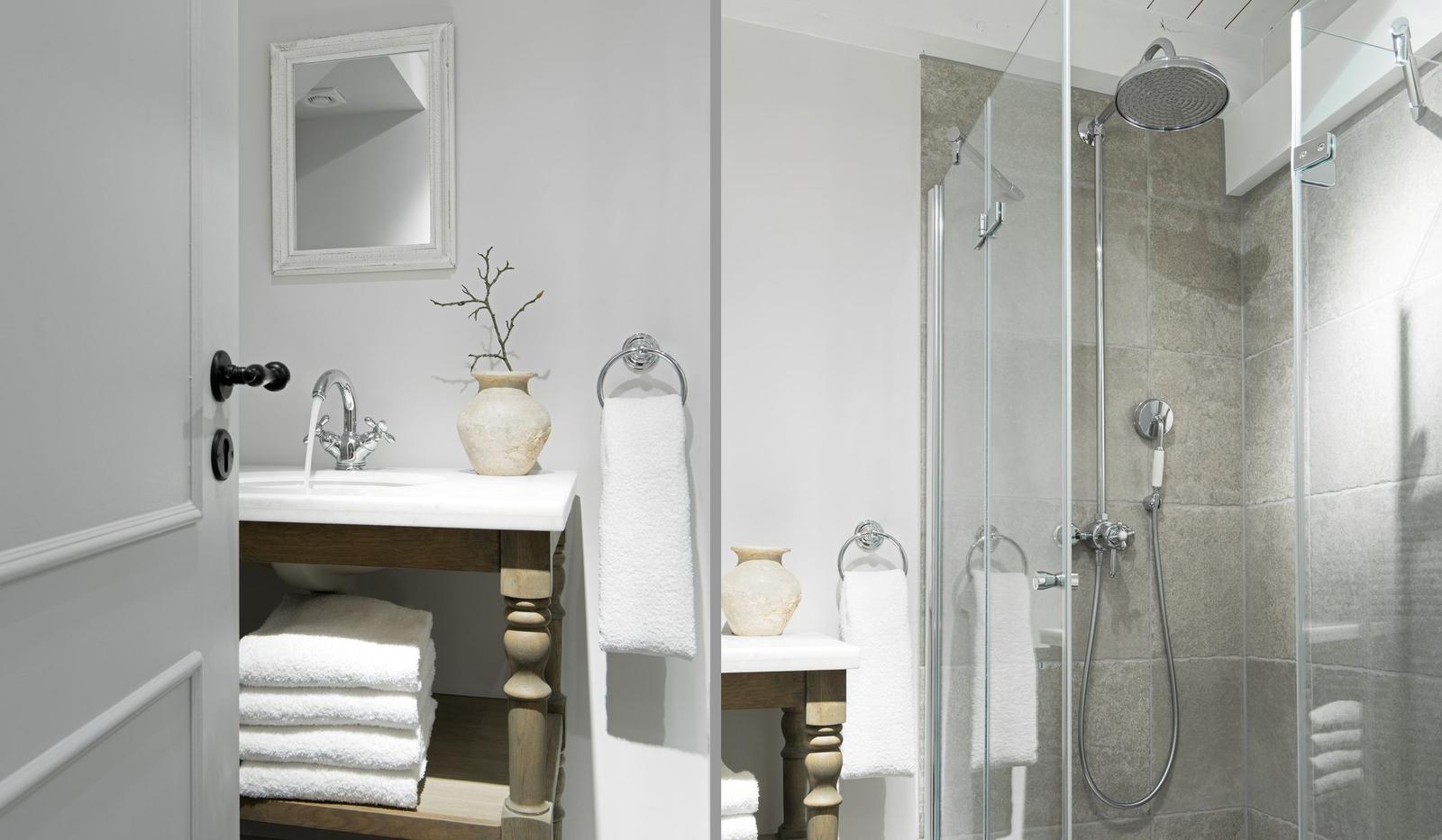 Bathroom with shower and sink. White walls, wooden vanity, and towels.
