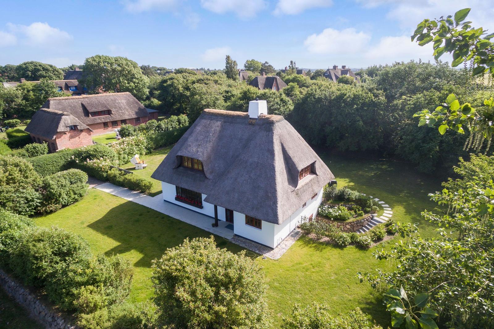 Haus mit Strohdach, Garten und Blick auf weitere Häuser.