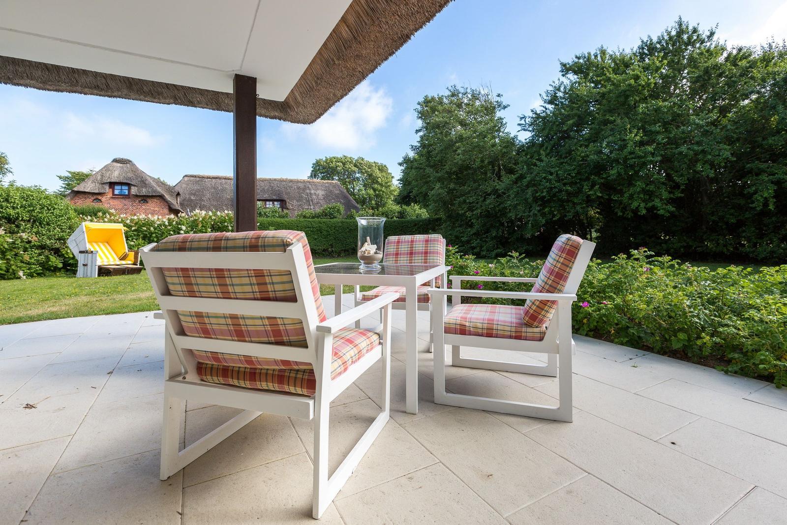 Terrasse mit weißen Stühlen und Tisch unter Dach