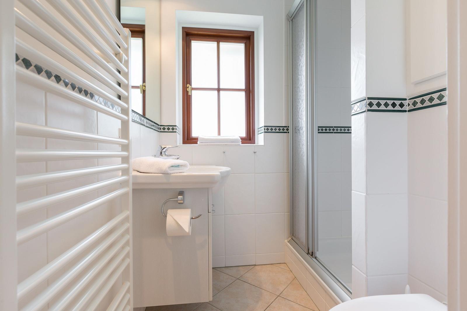 Badezimmer mit Dusche, Waschbecken und Fenster