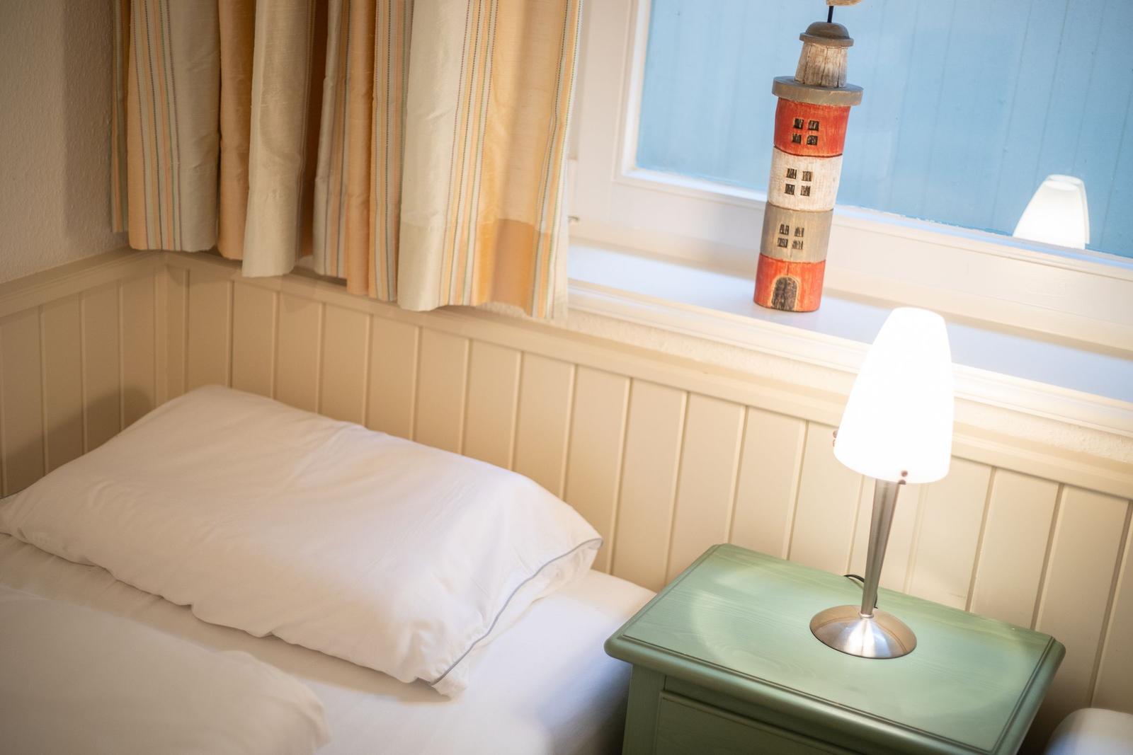 Schlafzimmer mit Bett, Nachttisch und Fenster mit Laterne.