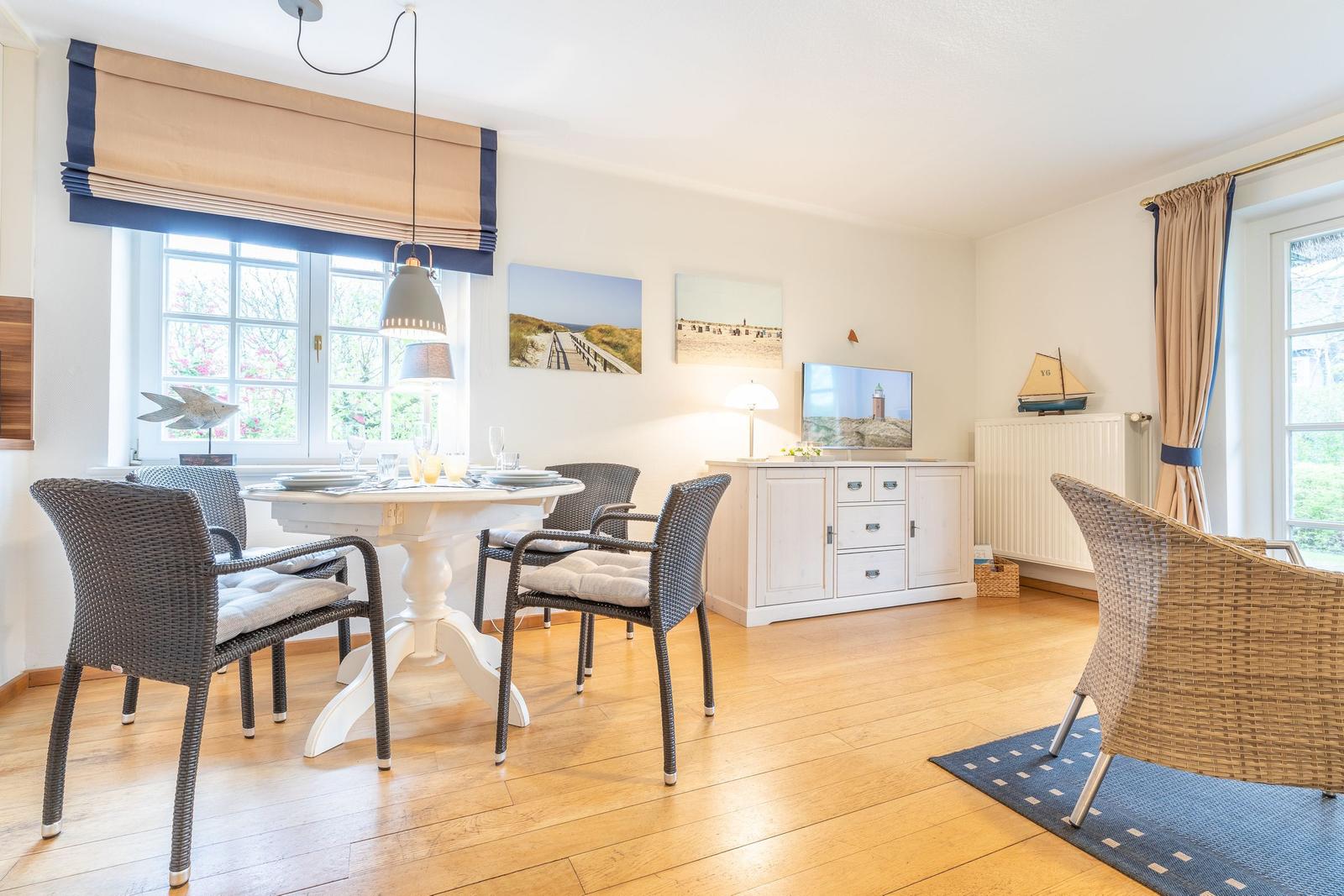 Esszimmer mit Esstisch, Stühlen und Fernseher an der Wand.