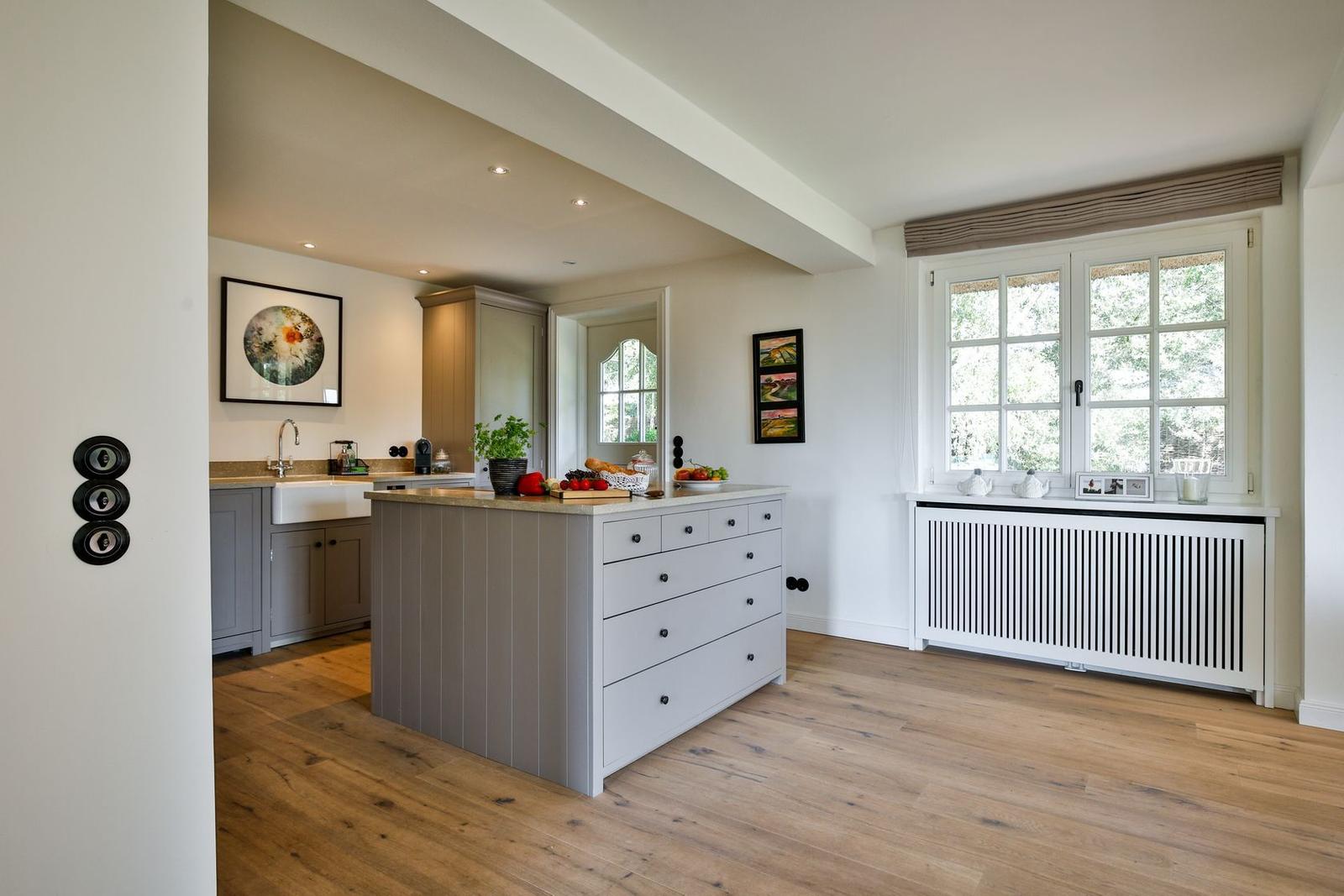 Kitchen with island, wooden floor, and window overlooking garden.