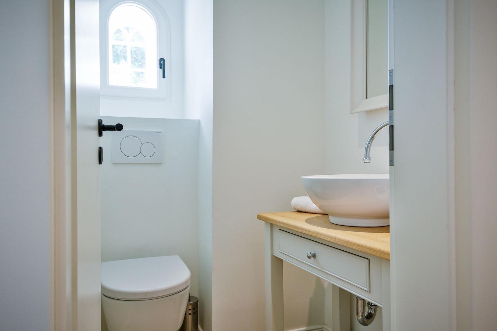 Bathroom with sink, mirror, and toilet under a window