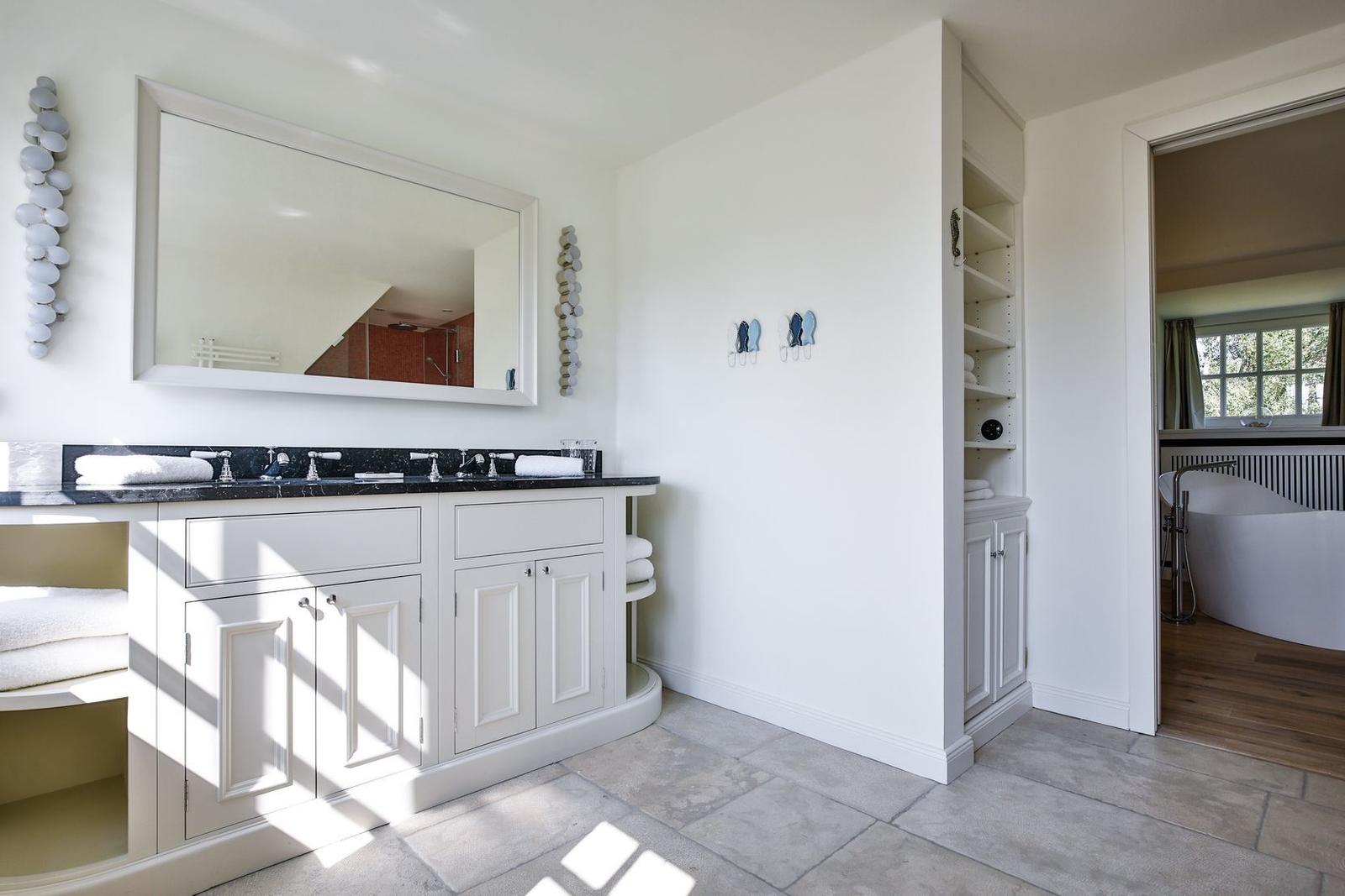 Bathroom with double sink, mirror, and freestanding bathtub.