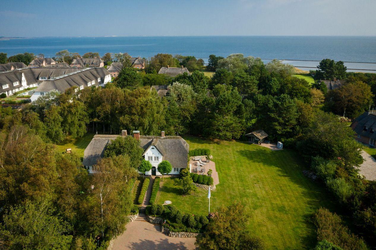 House with roof and garden, surrounded by trees and sea view