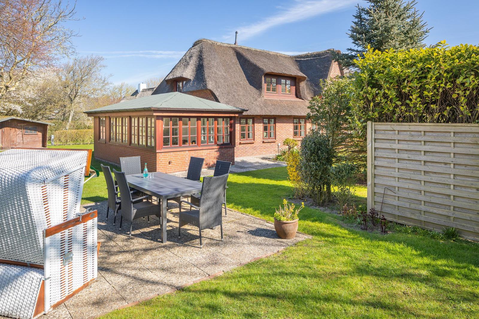 Haus mit Dachterrasse, Garten und Terrasse mit Tisch und Stühlen.