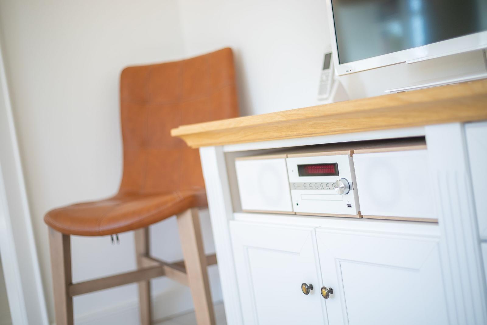 Holzschrank mit Fernseher und brauner Ledersitzbank