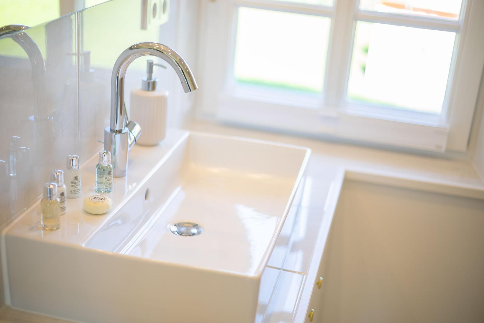 Waschbecken mit Wasserhahn und Seifenflaschen vor Fenster