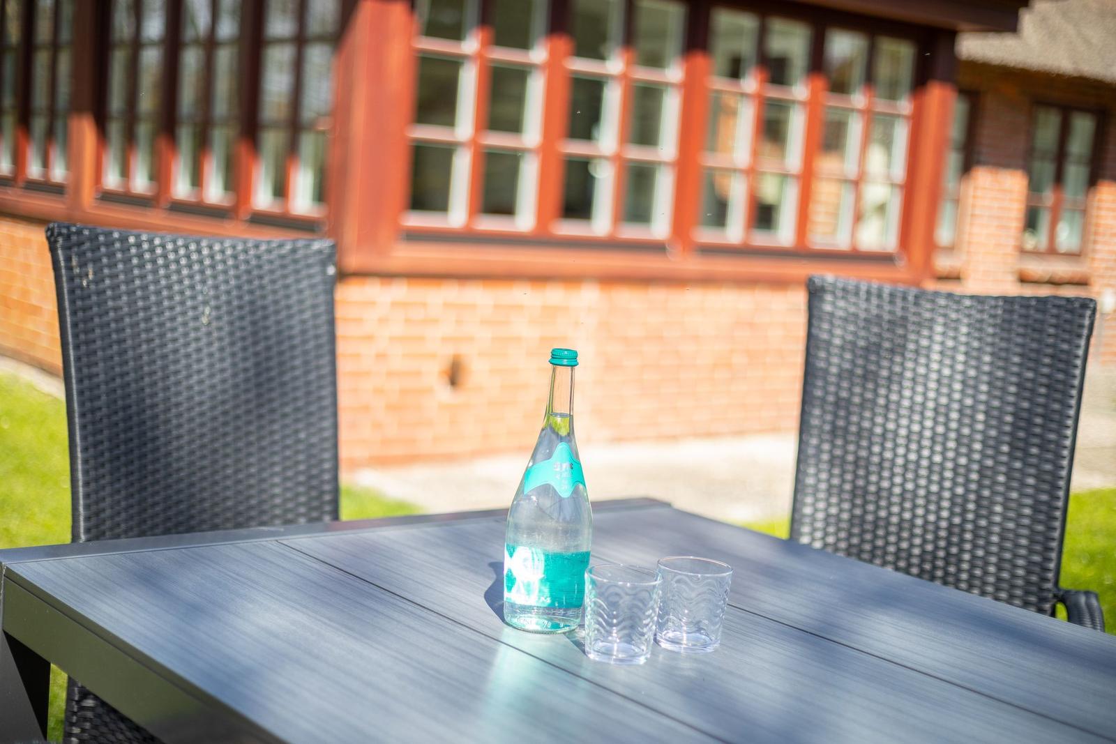 Außentisch mit Wasserflasche und Gläsern vor einem Haus