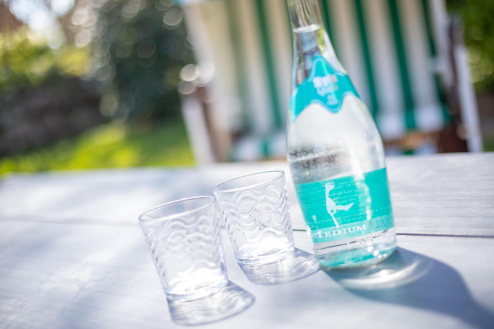 Auf dem Tisch stehen ein Wasserglas, ein weiteres Glas und eine Wasserflasche.
