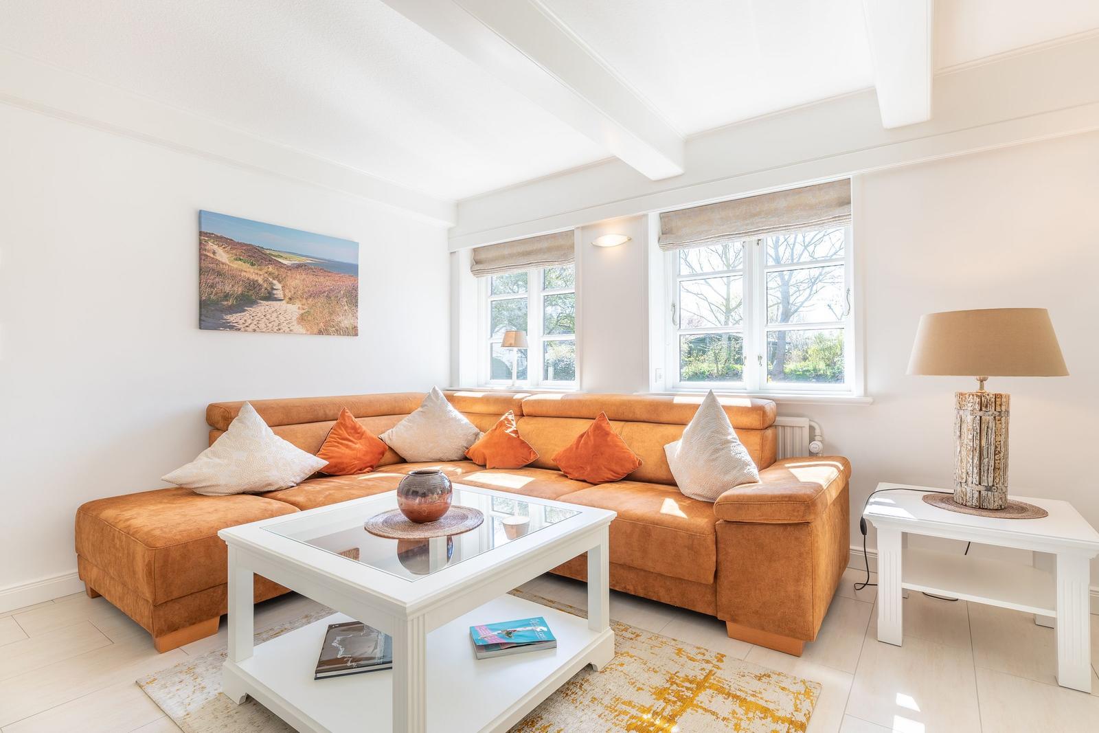 Wohnzimmer mit orangefarbenem Sofa, weißem Couchtisch und Fenstern.