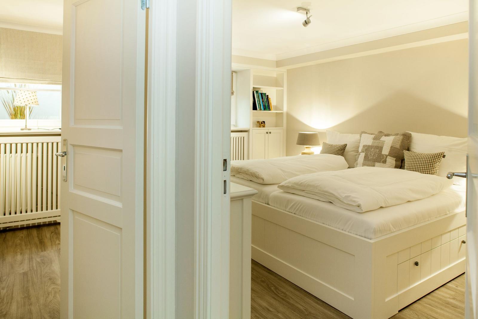 Bedroom with double bed, nightstand, and bookcase.