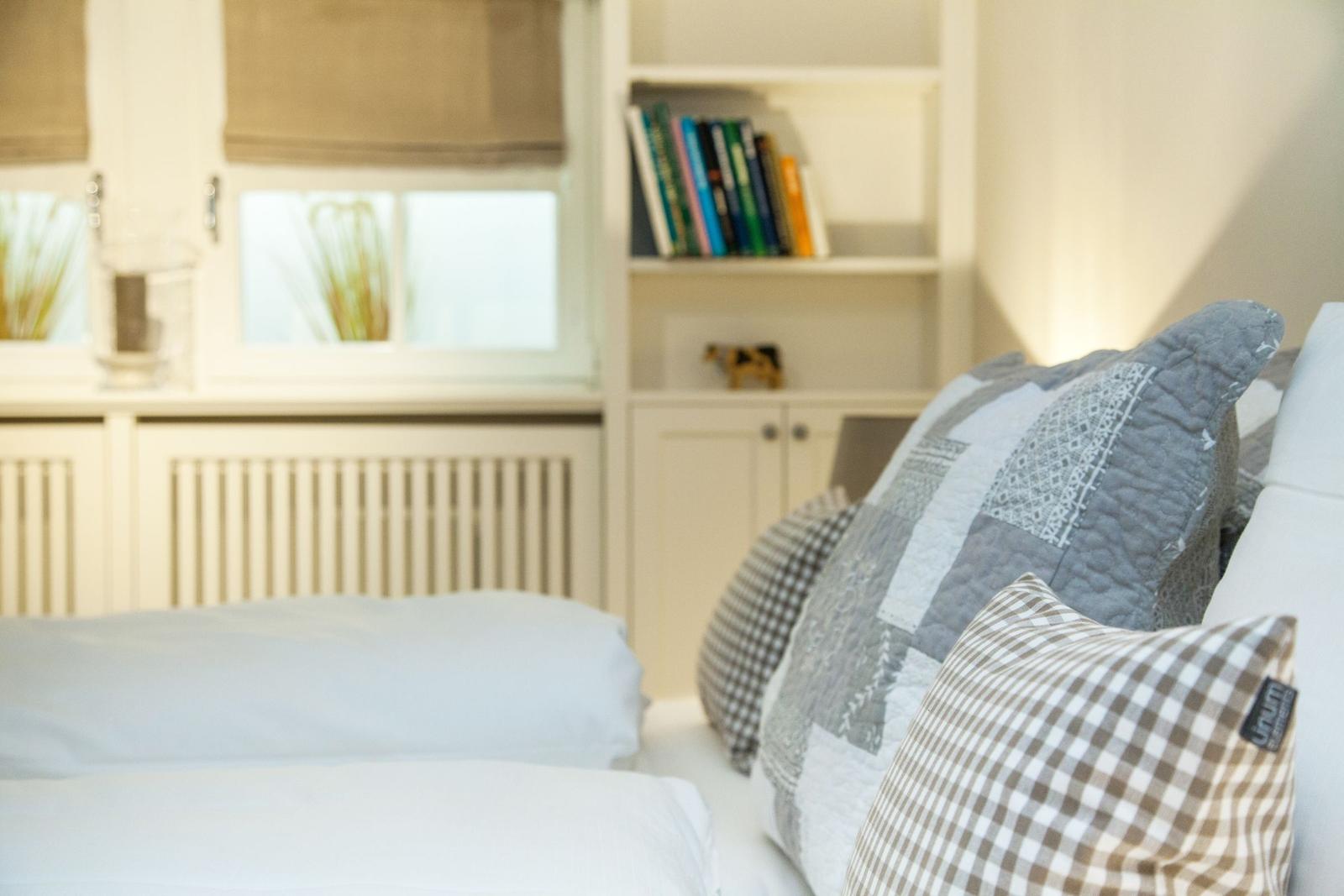 A bed with pillows and a bookcase in the background.