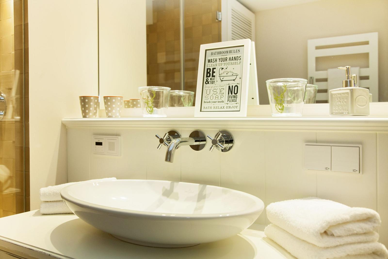 Sink with mirror, towels, and bath rules.