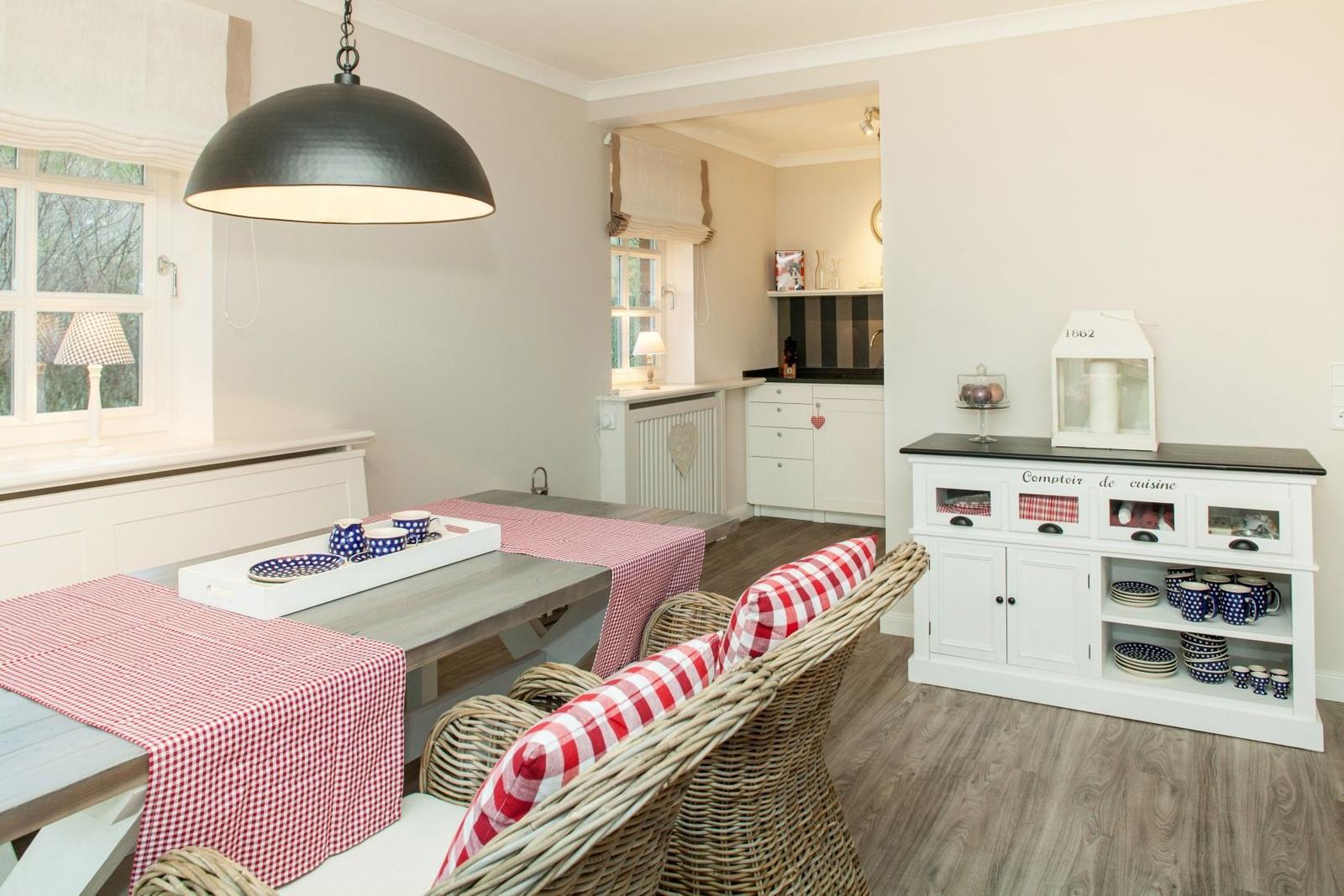 Dining area with table, chairs, and kitchen in the background.