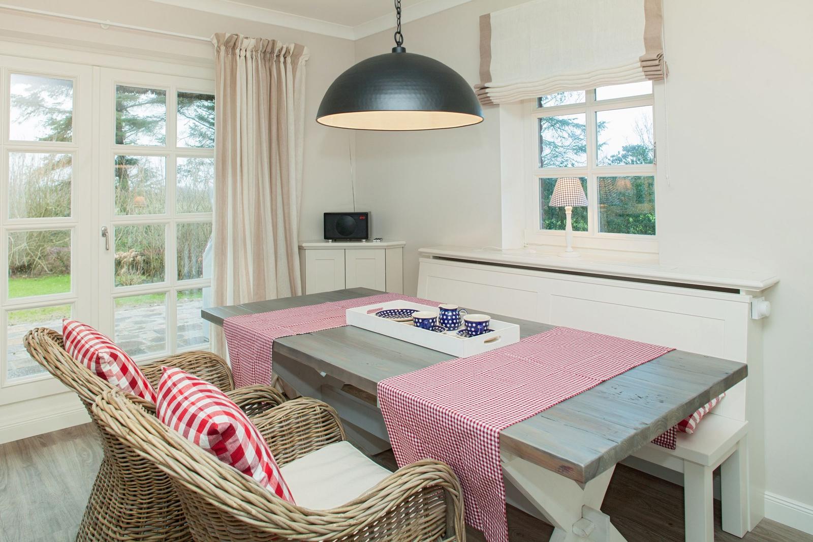 Dining room with wooden table, wicker chairs, and red table runner.