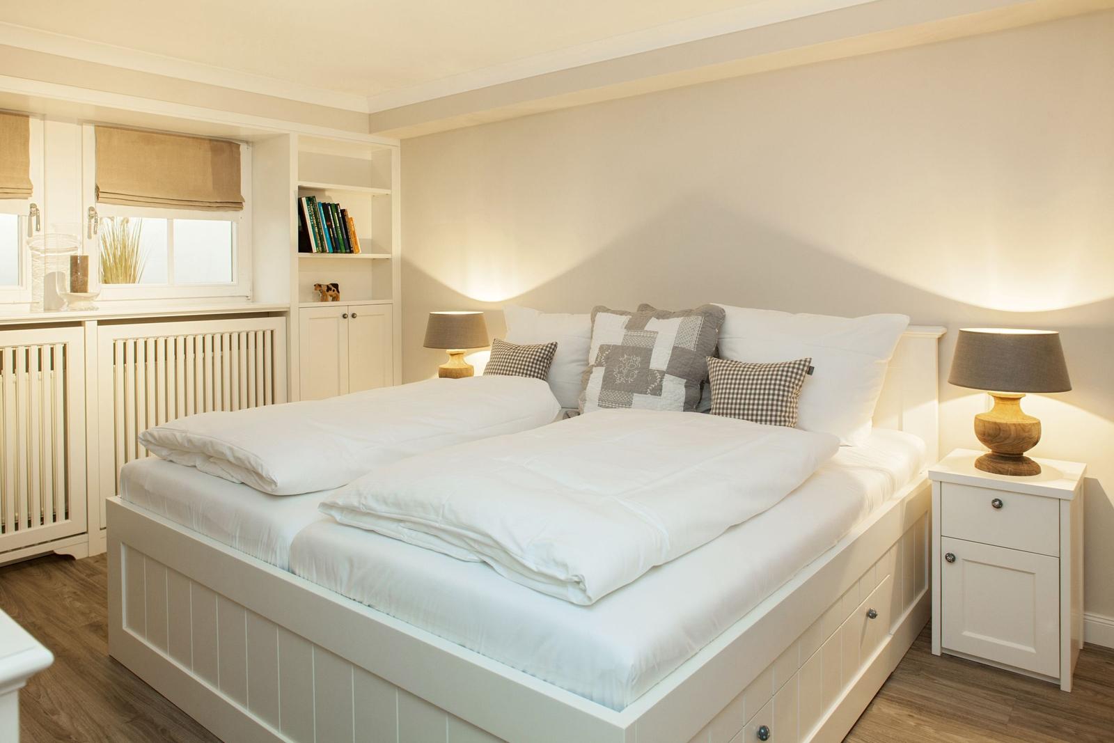 A bedroom with a double bed, nightstands, and a window with blinds.
