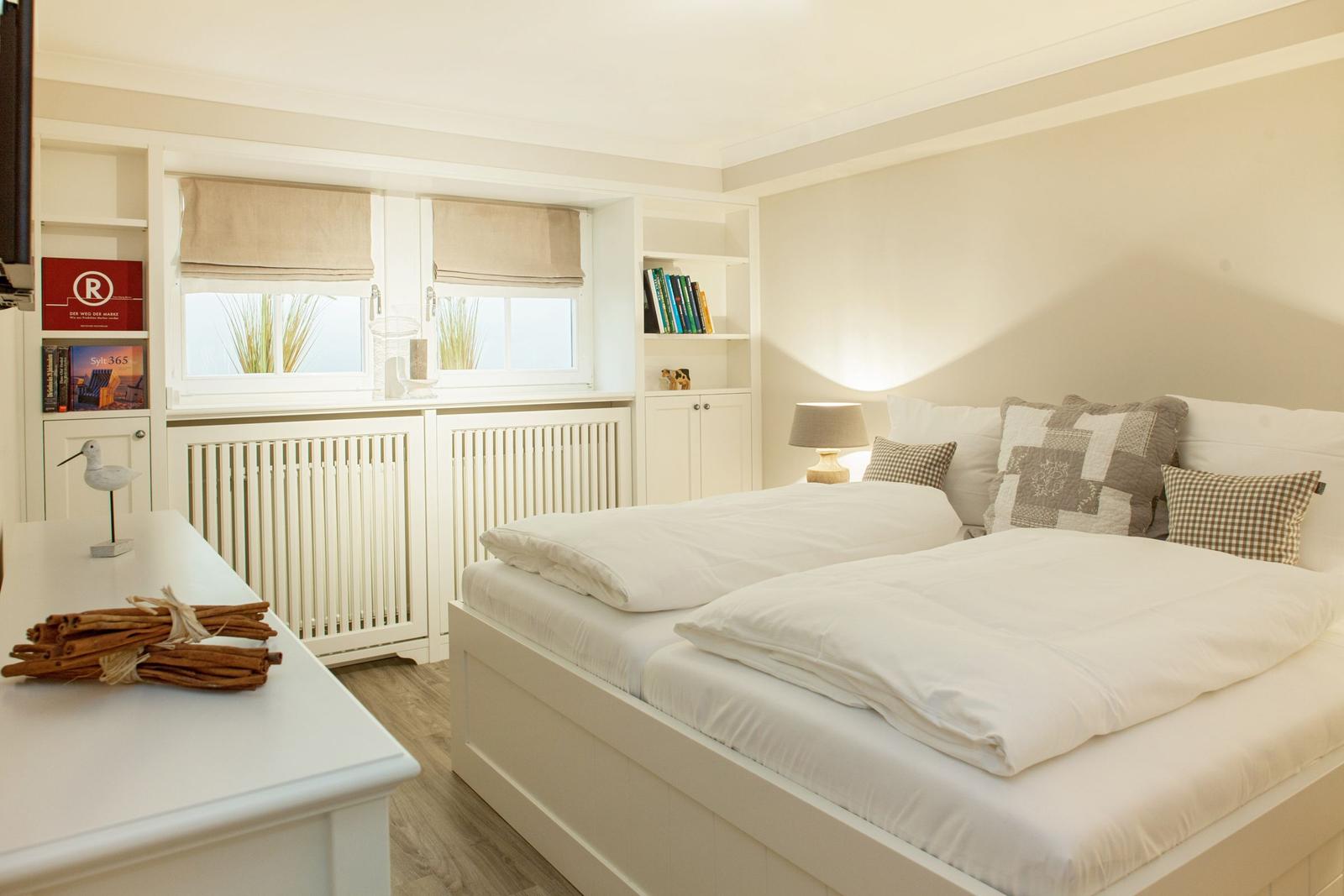 Bedroom with double bed, windows, and shelves.