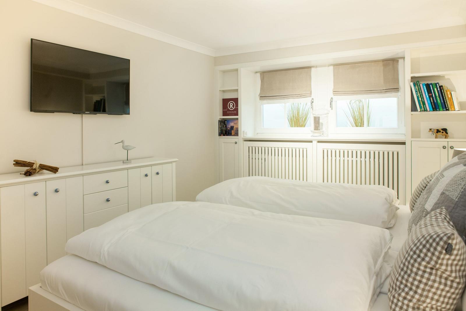 Bedroom with double bed, TV, and window with blinds.