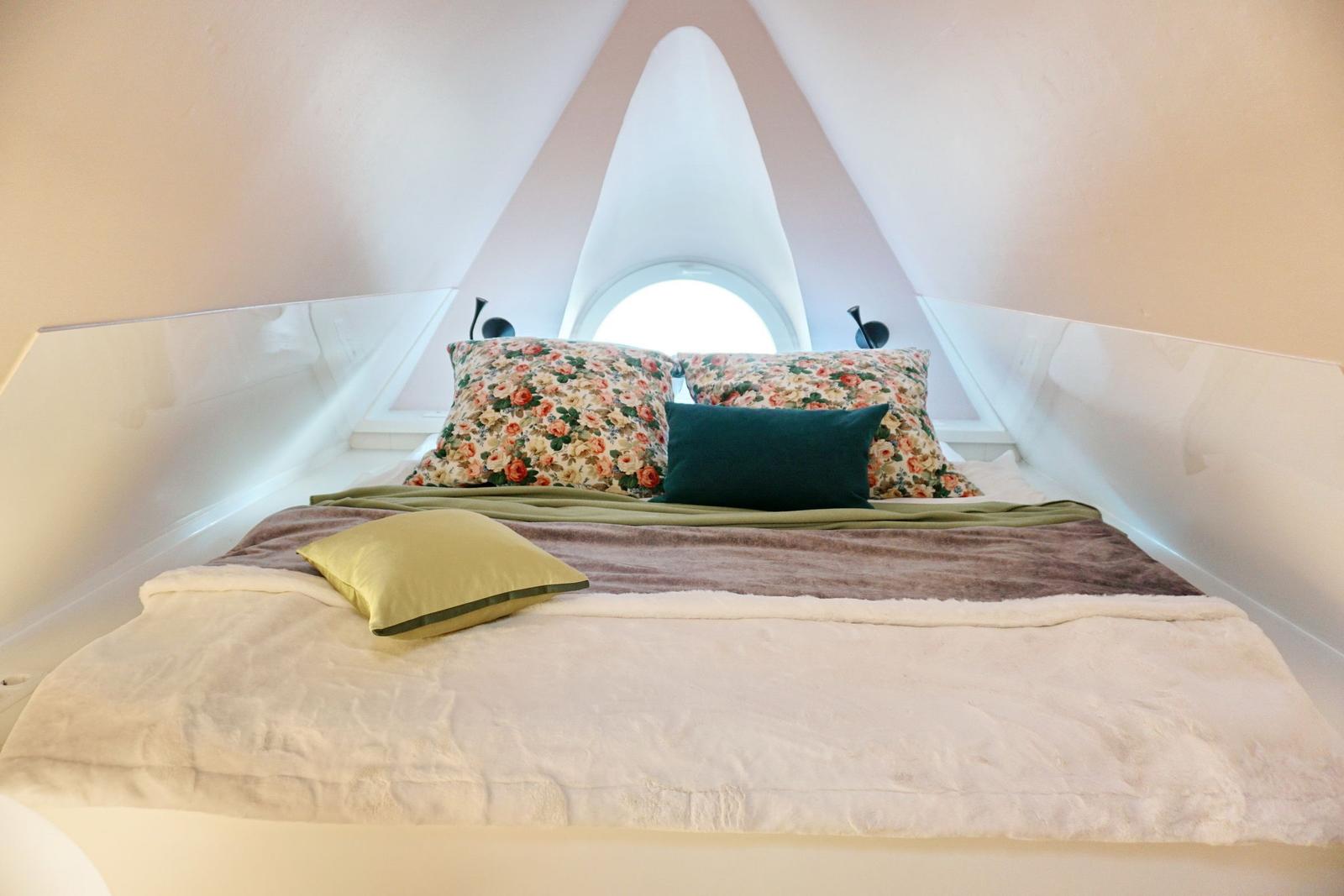 Schlafzimmer mit Bett unter Dachschrägen und runden Fenster