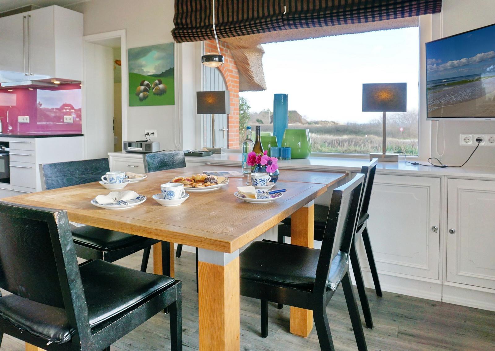 Esszimmer mit Holztisch, schwarzen Stühlen und Blick auf Landschaft.